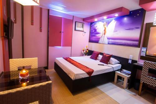 a bedroom with a king sized bed and a table at Hotel Dreamworld Las Pinas in Manila