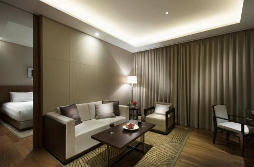 a hotel room with a couch and a table and a bed at Lotte City Hotel Jeju Airport in Jeju