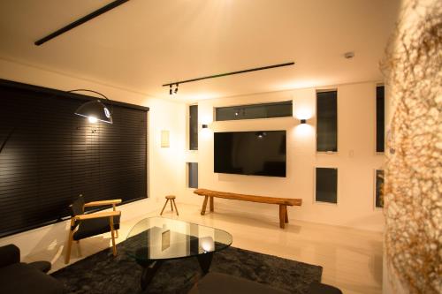 a living room with a table and a large screen tv at Ashina Bayfront Villa in Yokosuka