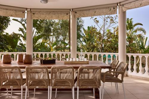 a wooden table and chairs on a porch at Luxury White House - Villa & Weddings - Family Villa Near the Sea to the Famous Zorbas Beach in Stavros