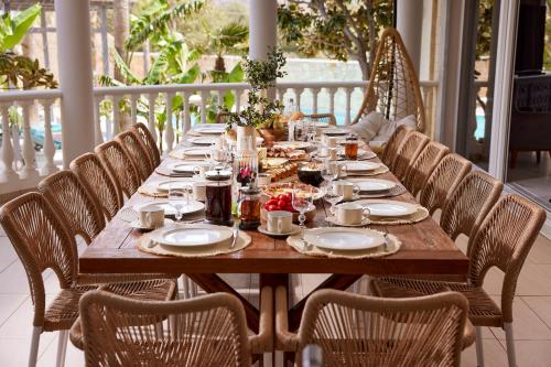 a long wooden table with chairs on a porch at Luxury White House - Villa & Weddings - Family Villa Near the Sea to the Famous Zorbas Beach in Stavros