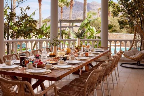 a long wooden table and chairs on a patio at Luxury White House - Villa & Weddings - Family Villa Near the Sea to the Famous Zorbas Beach in Stavros