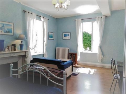 Sala de estar azul con cama y chimenea en Chambres et Tables d'Hotes Les Breuils, en Mariol