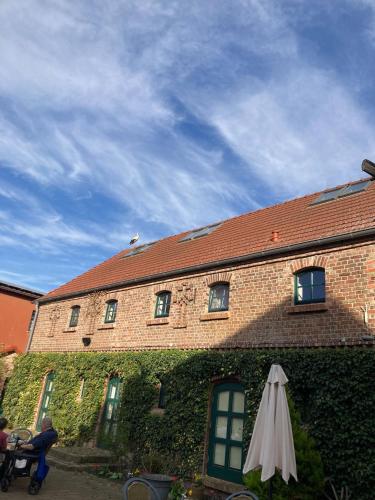 a brick building with an umbrella in front of it at Pensionszimmer im Fliederhof in Michendorf