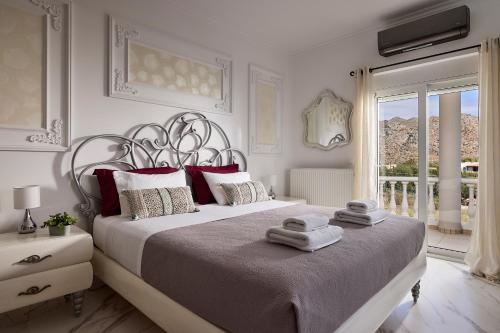 a white bedroom with a large bed and a window at Luxury White House - Villa & Weddings - Family Villa Near the Sea to the Famous Zorbas Beach in Stavros