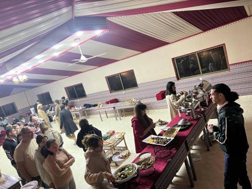 a group of people sitting at tables in a room with food at Rum Star Desert Camp in Wadi Rum