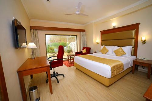 Habitación de hotel con cama, escritorio y TV. en Raj Park- Hill View, en Tirupati