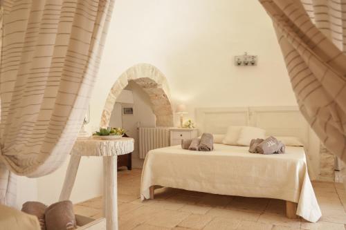 a bedroom with a bed and a table in a room at Trulli&Dimore - Casette Pricci in Castellana Grotte