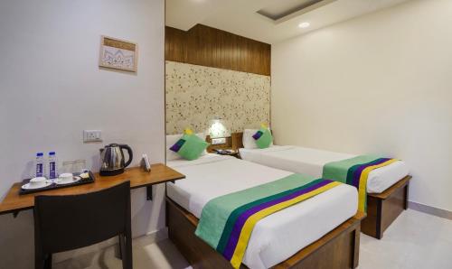 a hotel room with two beds and a desk and a desk at Treebo Park Palace in Guwahati