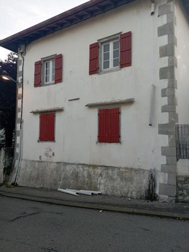 um edifício branco com janelas vermelhas fechadas numa rua em logement entier 5 personnes em Irissarry