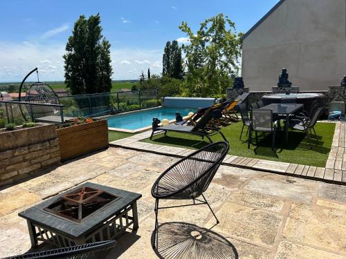 un patio avec une table et des chaises et une piscine dans l'établissement La maison du chêne, à Chaignay
