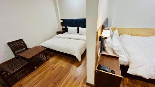 Habitación con 2 camas, mesa y silla en Hotel Ocean Mountain View, en Manali