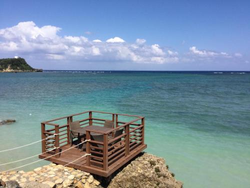a wooden table on the shore of the ocean at Hotel Oceans Nakijin in Nakijin
