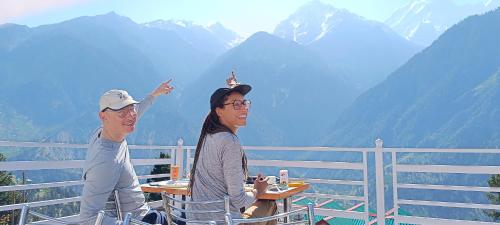 a man and woman sitting at a table in front of mountains at Kin Vatika Homestay in Kalpa