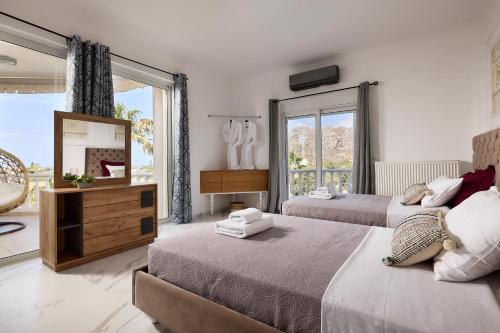 a bedroom with two beds and a large window at Luxury White House - Villa & Weddings - Family Villa Near the Sea to the Famous Zorbas Beach in Stavros