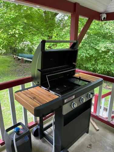 - un barbecue installé sur une terrasse couverte avec une table dans l'établissement Le chalet du bout du monde, en bord de rivière !, à Grez-sur-Loing