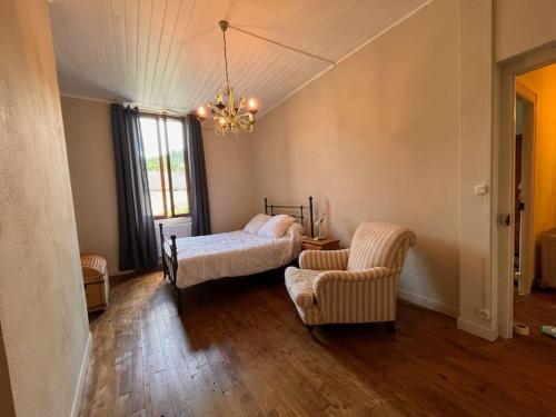 - une chambre avec un lit, une chaise et un lustre dans l'établissement Maison de charme au calme, à Nedde
