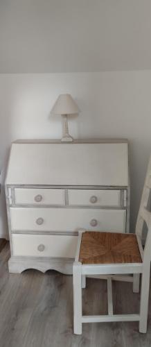 a white dresser with a lamp and a chair at Au fil de l'Orge in Saint-Chéron