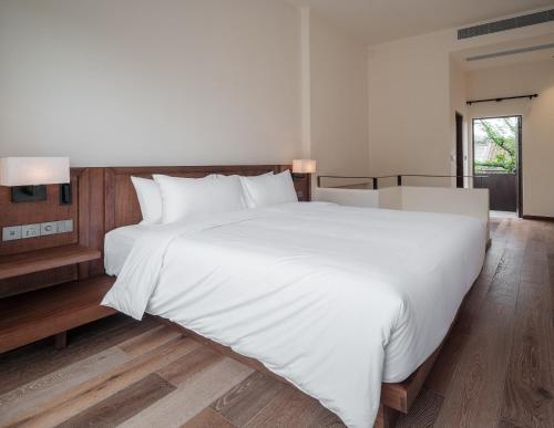 a large white bed with white sheets and pillows at Sanhe Daoli Resort in Qingyuan