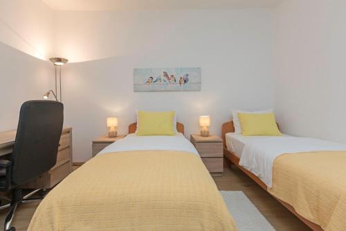 a bedroom with two beds and a desk with two lamps at Apartman Oliva in Pula