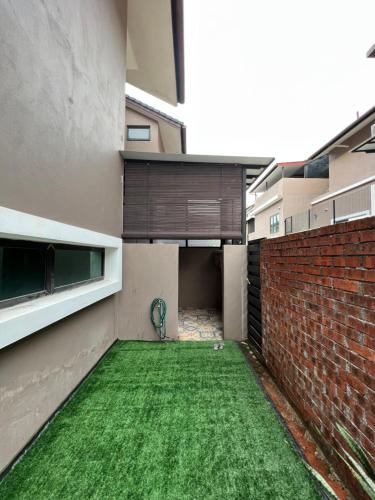 un patio con césped verde en un edificio en Lapan Ompek Homestay 3 Bedrooms en Nilai