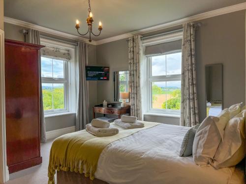 a bedroom with a large bed with two windows at High House Cottage Southwaite in Southwaite