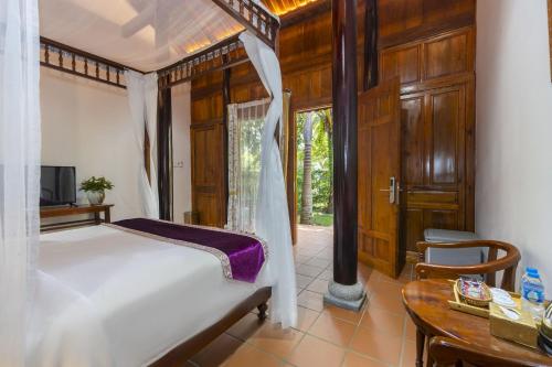 a bedroom with a white bed and a table and a table at Maison Du VietNam Resort & Spa in Phu Quoc