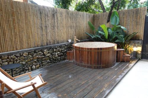a hot tub on a wooden deck with a fence at Sanhe Daoli Resort in Qingyuan