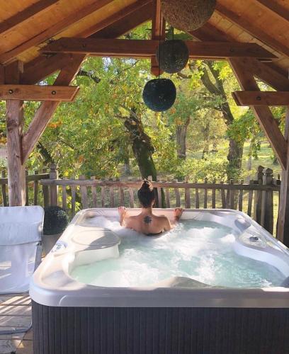 un homme assis dans un bain à remous dans une arrière-cour dans l'établissement Cabane spa, à Rion-des-Landes
