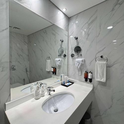 a white bathroom with a sink and a mirror at Emirates Grand Hotel in Dubai