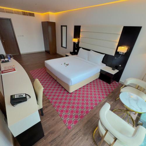 a bedroom with a large white bed and a desk at Emirates Grand Hotel in Dubai