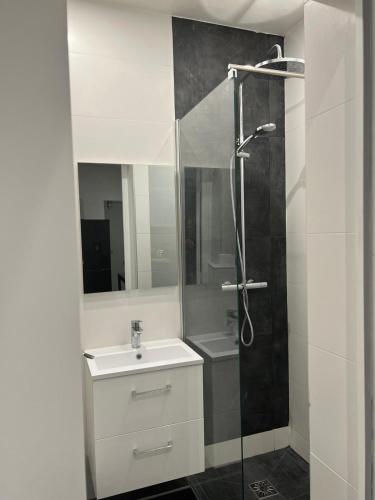 une salle de bain avec un lavabo blanc et une douche dans l'établissement Appartement Paris - La Defense, à La Garenne-Colombes