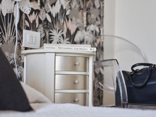 a bed with a dresser and a black and white wallpaper at Hotel Sole in Cannero Riviera