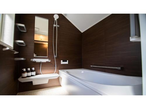 ein Badezimmer mit einer Badewanne und einem Waschbecken in der Unterkunft Kominka Hotel kurasu - Vacation STAY 24275v in Tatsuno