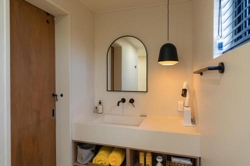 a bathroom with a sink and a mirror at Dazayo Anseong Gangsaengi House - Pet Friendly in Seogwipo