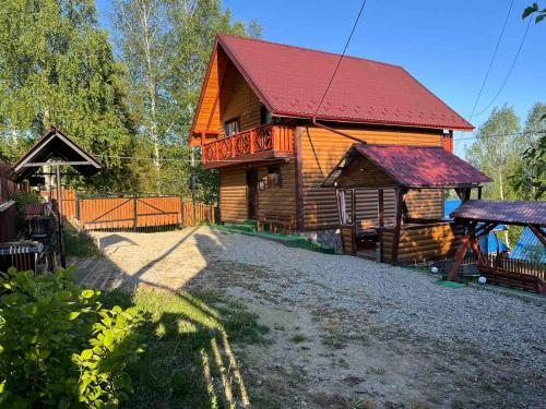 une grande cabane en bois avec un toit rouge dans l'établissement Сімейний котедж КРАЄВИД, à Mykulychyn