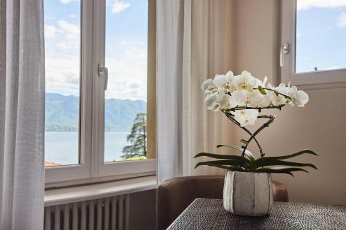 a vase with white flowers on a table in front of a window at Hotel Sole in Cannero Riviera
