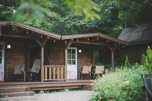Cabaña de madera con sillas y porche en Premium villa glamping log cabin with stars and bonfire en Hokuto