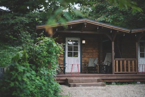 drewniany domek z werandą i krzesłem z przodu w obiekcie Premium villa glamping log cabin with stars and bonfire w mieście Hokuto