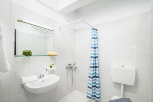 een witte badkamer met een wastafel en een spiegel bij Elen-Mari in Chersonissos