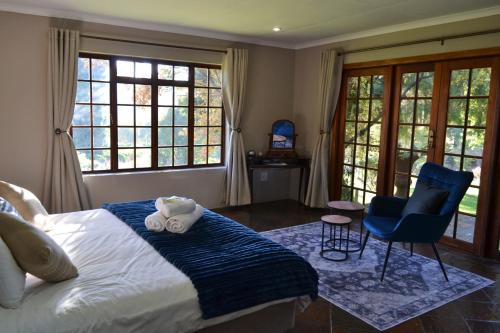a bedroom with a bed and two chairs and windows at Remi Lodge in Dullstroom