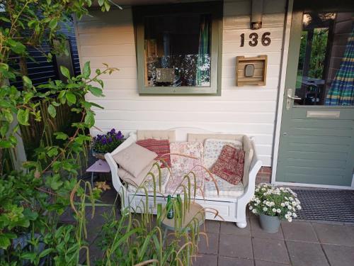 a white couch sitting on the porch of a house at Vrije Vogels tuin met privacy in Warmenhuizen