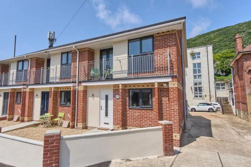 a brick apartment building with a balcony on a street at *Malt House* a Cosy Family Seaside Hideaway in Ventnor