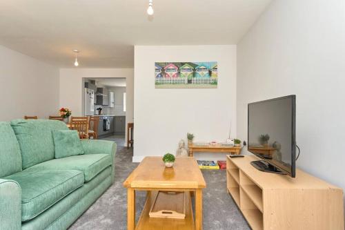 a living room with a green couch and a table at *Malt House* a Cosy Family Seaside Hideaway in Ventnor