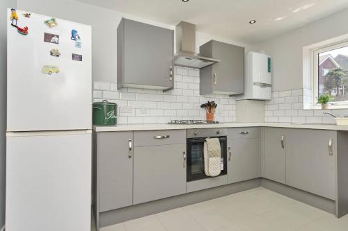 a kitchen with white cabinets and a refrigerator at *Malt House* a Cosy Family Seaside Hideaway in Ventnor