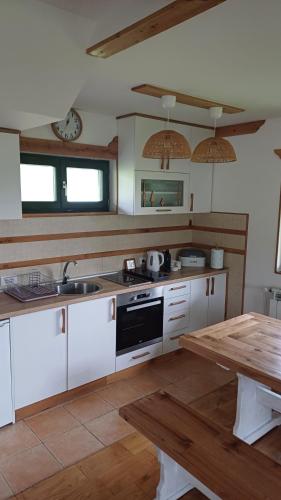 a kitchen with white cabinets and a wooden table at Casa Mila Zlatibor in Zlatibor