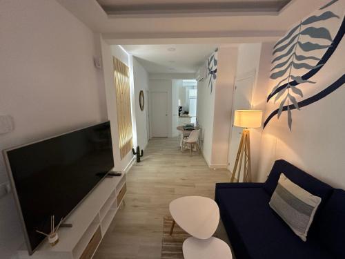 sala de estar con sofá azul y TV de pantalla plana en Apartamento Andalucía 33 Izquierda, en Málaga
