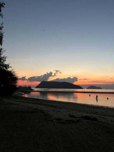 a sunset on a beach with people in the water at Sunset beach villa 7 O3 villas in Haad Pleayleam