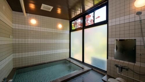 a bathroom with a bath tub with a window at Onsen Urashima in Onomichi