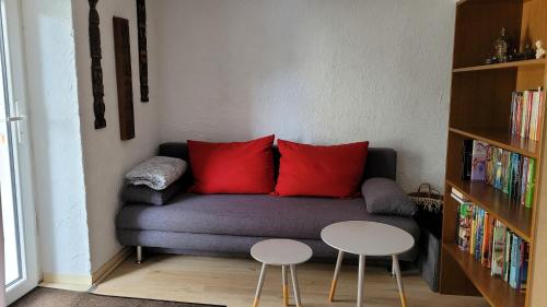 a living room with a couch with red pillows and two tables at Pfälzer LebensArt in Rieschweiler-Mühlbach